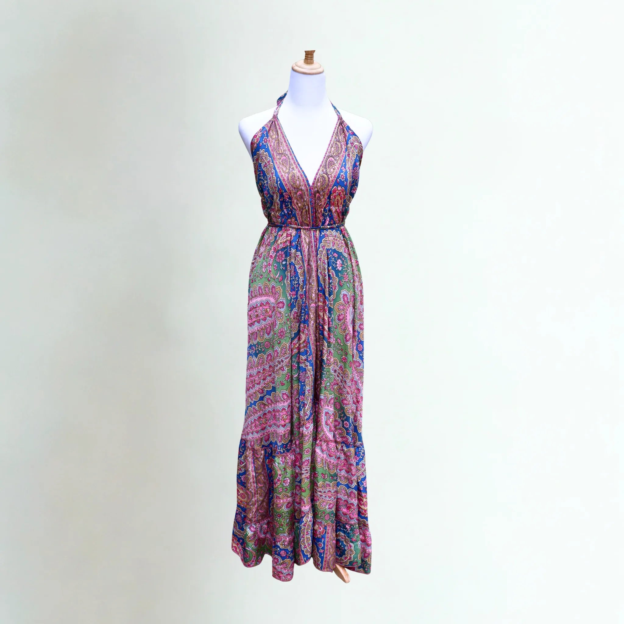 Elegant breathable silk summer dress in bright pink, green and blue paisley, open back and adjustable halter neck ties on a mannequin.