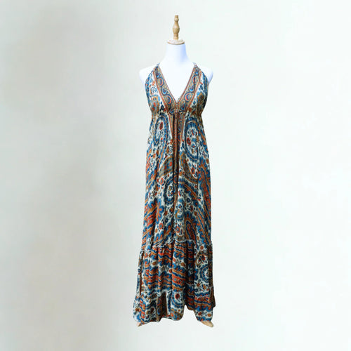 Elegant breathable silk summer dress in teal and amber organic paisley, open back and adjustable halter neck ties on a mannequin.