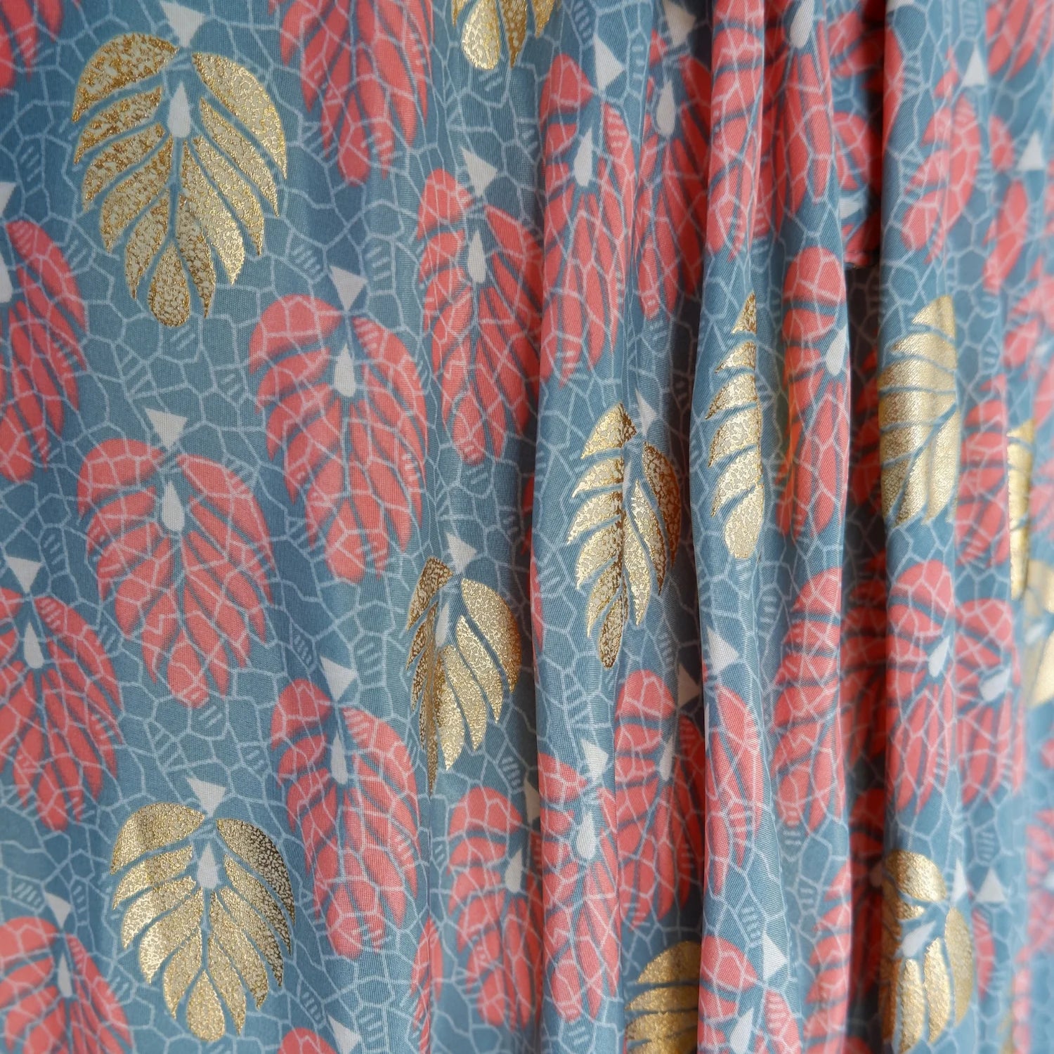 Fabric with a leaf pattern featuring red, gold, and blue colors.