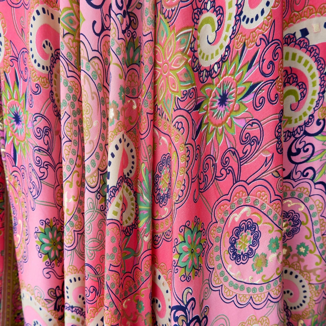 Colorful paisley patterned fabric on a pink background